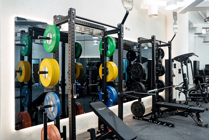 Gym with weight racks, colorful plates, and workout benches.