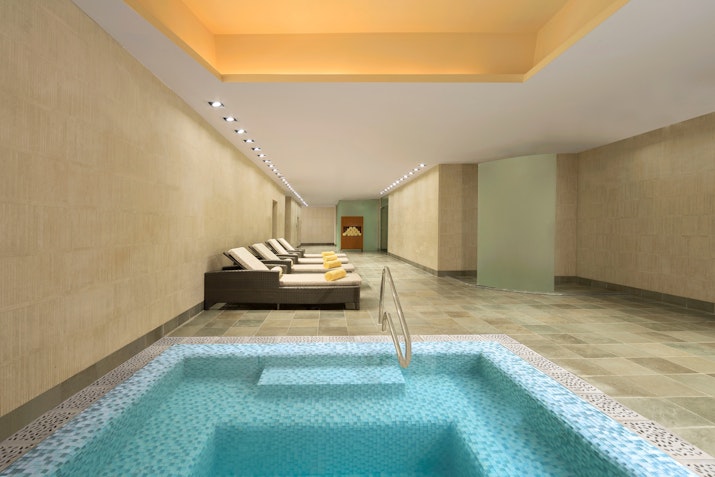 Tranquil spa room with a soothing pool, lounge chairs, and soft lighting.