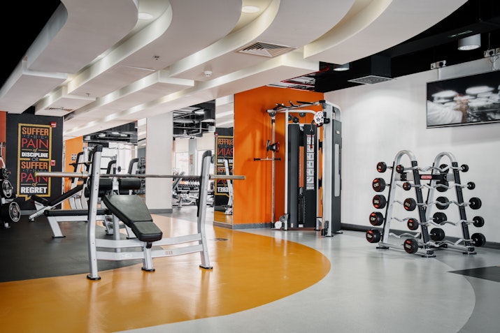Gymmito Fitness Club, The Pearl Modern gym with workout equipment, dumbbells, and bold orange and gray flooring