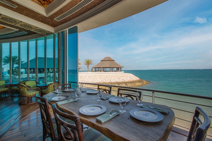 Restaurant with a seaside view, set table, and panoramic windows.