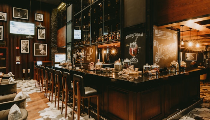 Hilton Doha The Pearl Kitchen Stylish bar with vintage decor, stools, and framed photographs on the wall.