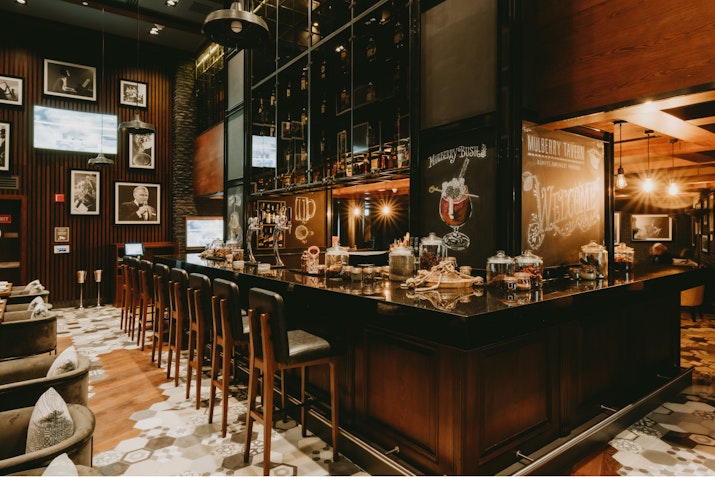 Stylish bar with vintage decor, stools, and framed photographs on the wall.