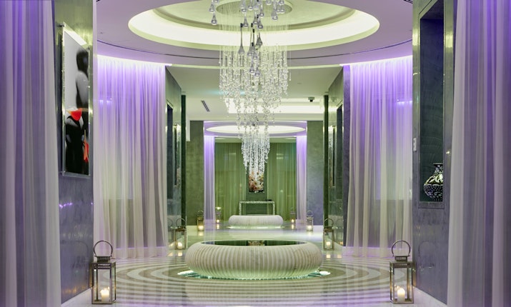 Luxurious spa corridor with chandeliers, soft lighting, and elegant decor.