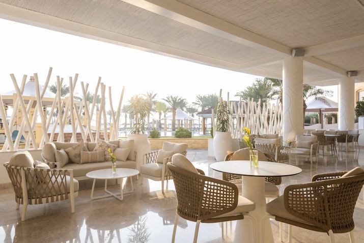 Outdoor seating area with comfortable furniture, plants, and a view of the resort pool