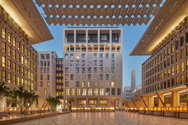 Modern building complex with an open courtyard and geometric architectural design at dusk.