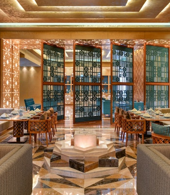 Marsa Malaz Kempinski Five Star Dining Modern restaurant interior with decorative partitions and elegant seating arrangements.