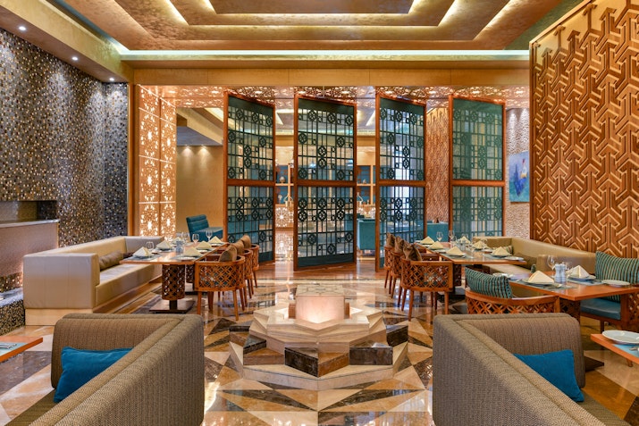 Modern restaurant interior with decorative partitions and elegant seating arrangements.