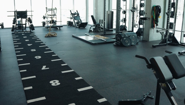 STAGE Fitness Spacious gym with numbered fitness turf, weightlifting equipment, and large windows