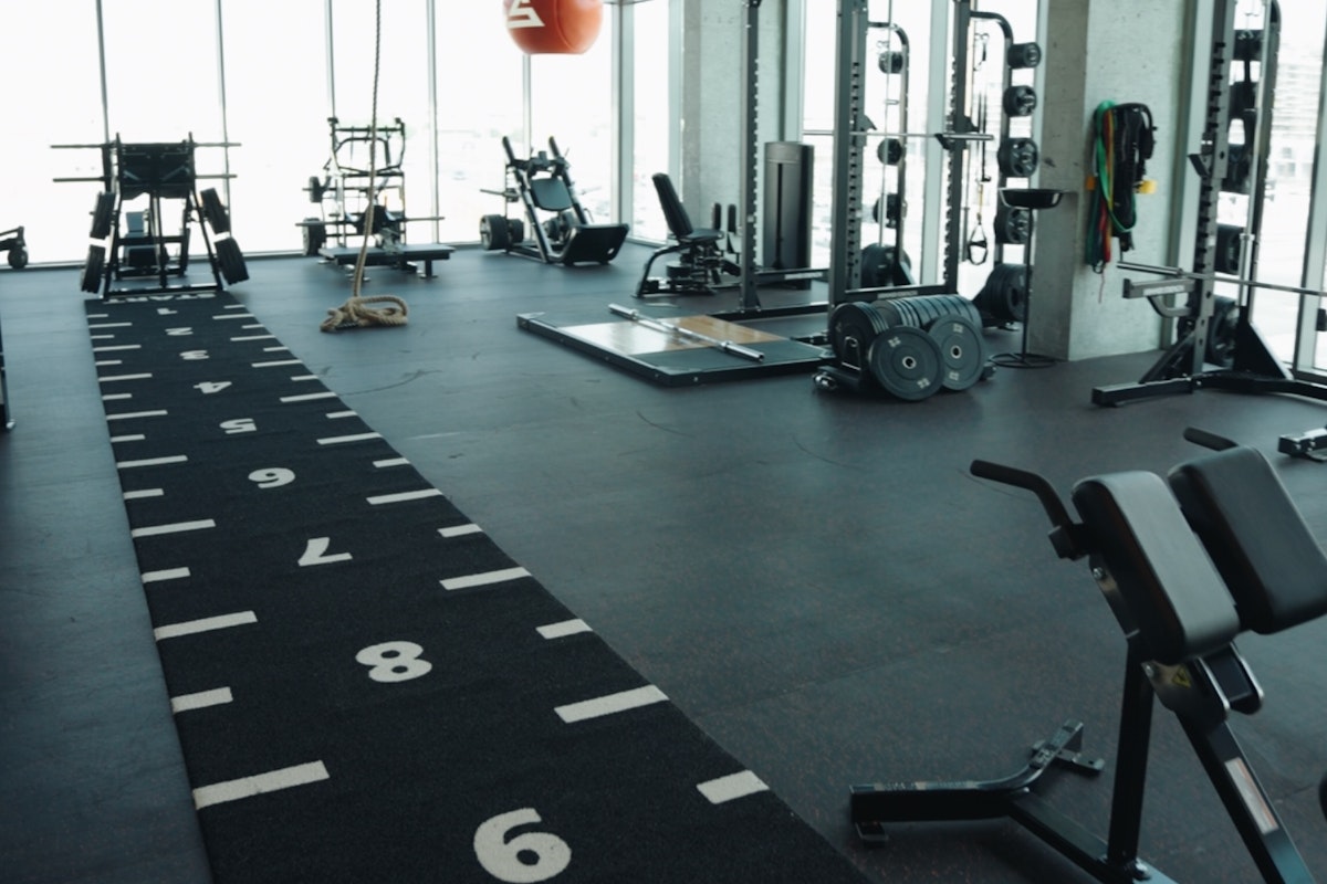 Spacious gym with numbered fitness turf, weightlifting equipment, and large windows