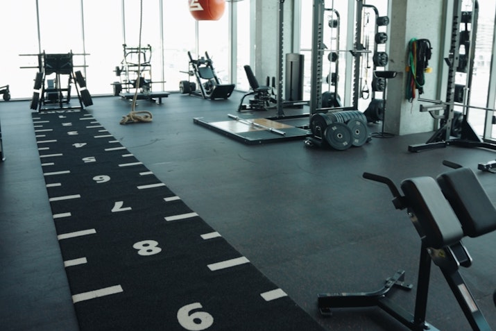 Spacious gym with numbered fitness turf, weightlifting equipment, and large windows
