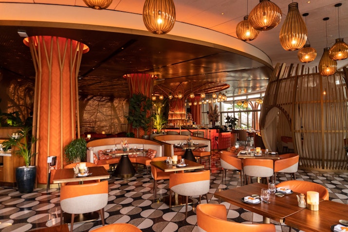 A stylish and warm restaurant interior with orange lighting, contemporary seating arrangements,