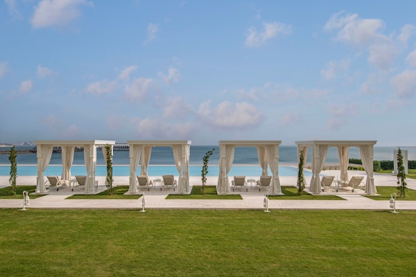 Outdoor seating area with white cabanas overlooking a beach and ocean.