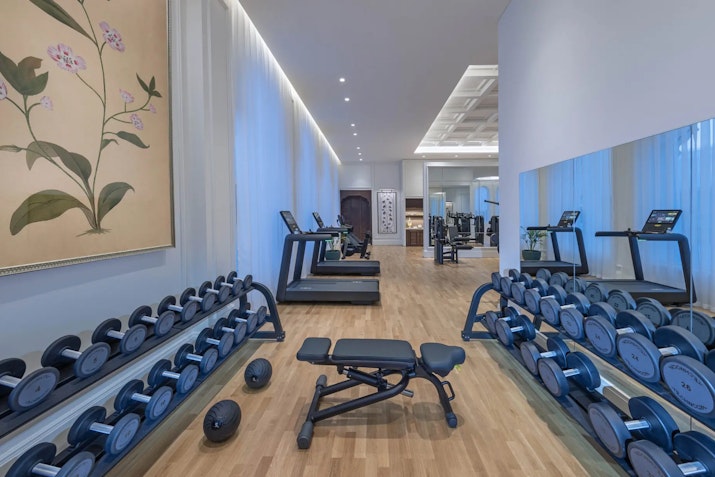 Modern gym with dumbbells, treadmill, and workout equipment.