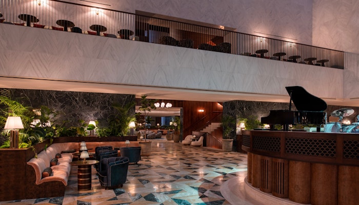 The Ned, Doha Elegant hotel lobby with a grand piano, luxurious seating, and a beautiful marble floor design.