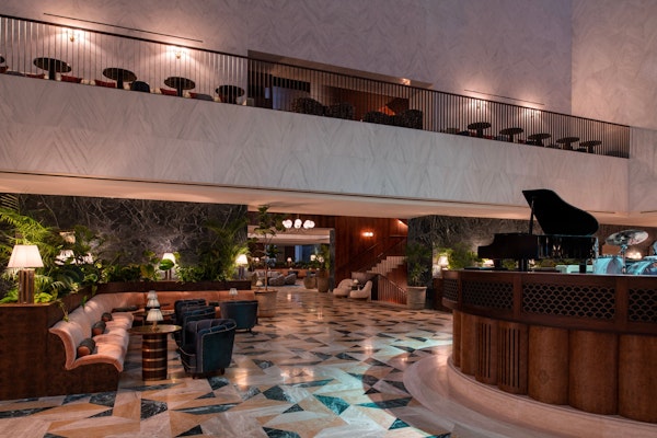 Elegant hotel lobby with a grand piano, luxurious seating, and a beautiful marble floor design.