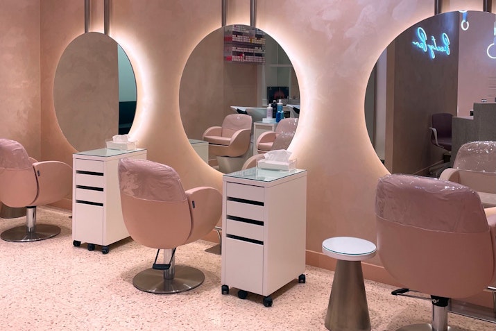 Beauty salon with modern pink chairs, mirrors, and vanity stations