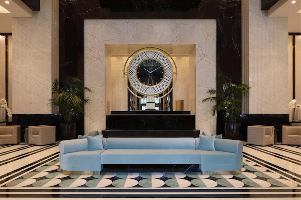 Luxurious hotel lobby with a large round mirror, a blue sofa, and elegant marble flooring
