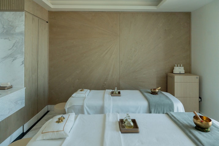 Luxury spa treatment room with massage beds, soft linens, and soothing decor