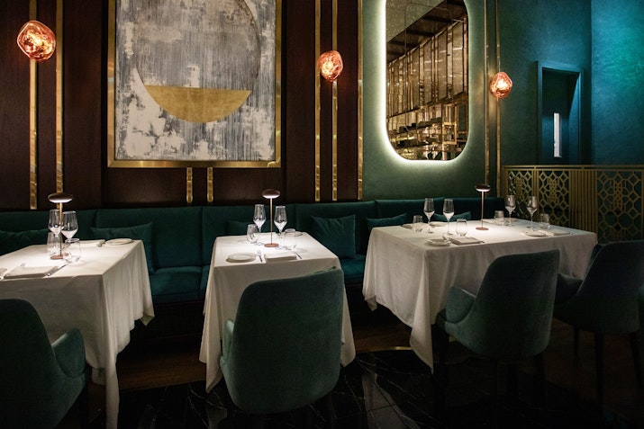 Elegant restaurant with velvet seating, fine dining tables, and ambient lighting.