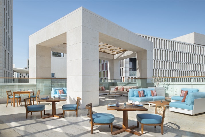Outdoor seating area with tables and chairs, featuring blue cushions and a pergola.