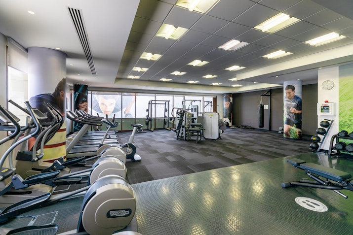Modern gym with cardio equipment, weight machines, and large windows