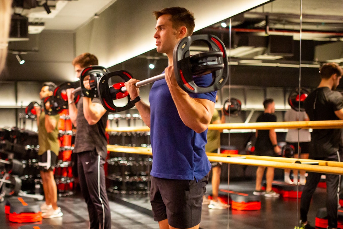 Man performing weightlifting exercises with a barbell in a gym class.
