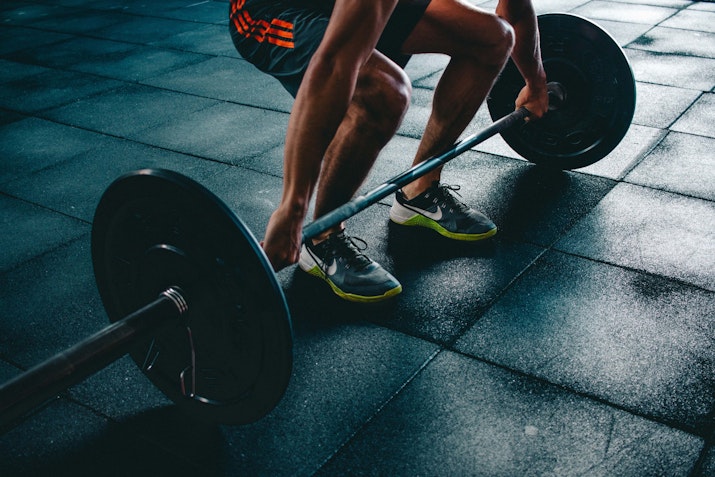 Person lifting a barbell in a gym.