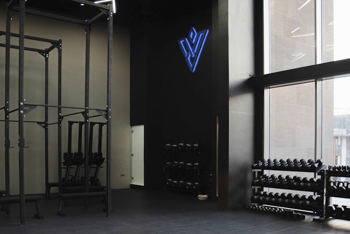 Modern gym with dumbbell racks and a fitness studio with branding