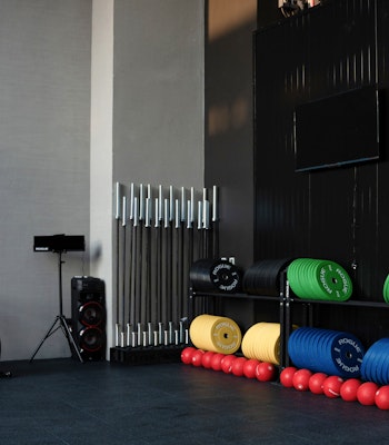 Specialist Instructors Two exercise bikes beside colorful weighted balls and equipment stacked on racks in a gym.