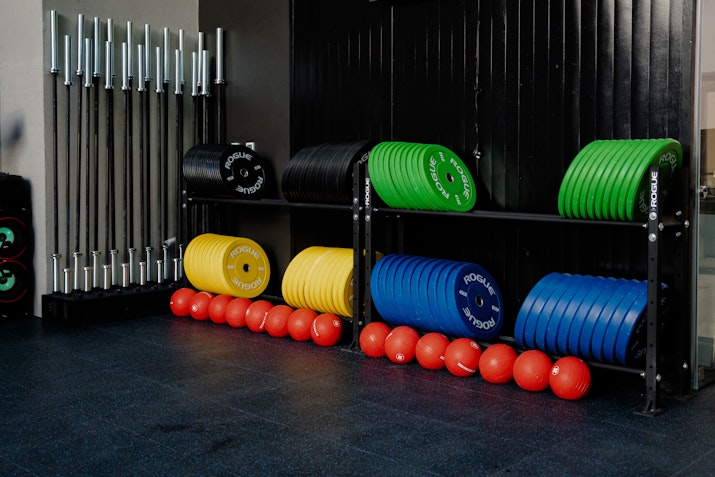 Signature class VaultFit Weight plates and medicine balls neatly organized on racks in a gym