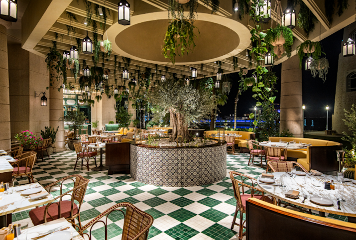Outdoor dining area with hanging plants and a fountain, offering a cozy atmosphere with a checkered floor.