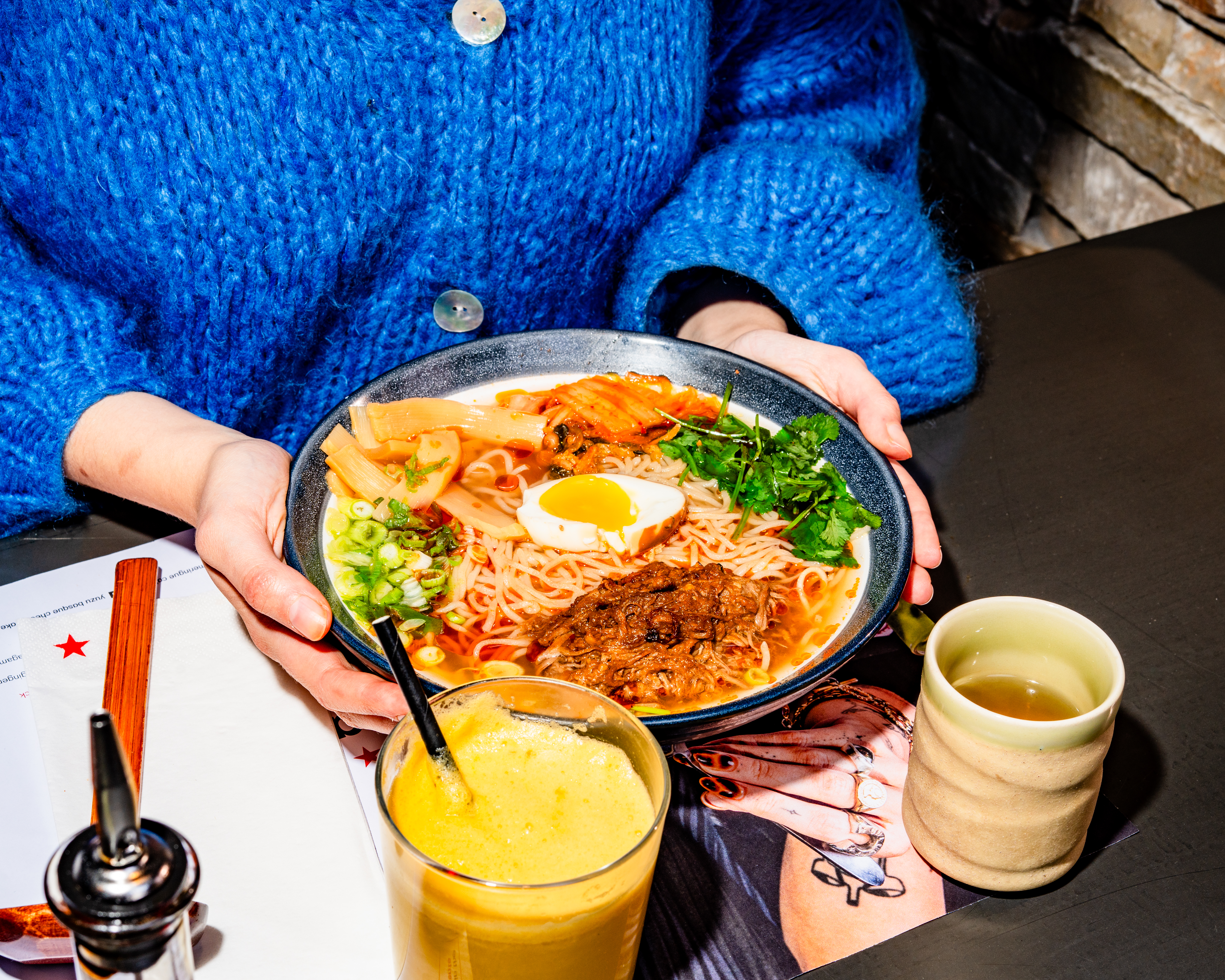 hands holding a bowl of a fresh tantamen beef brisket ramen