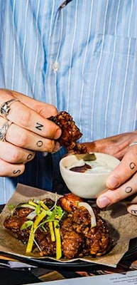 a person dipping hot honey fried chicken into zesty mayo