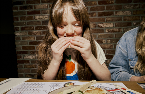 a little girl take a big bite of a bao bun