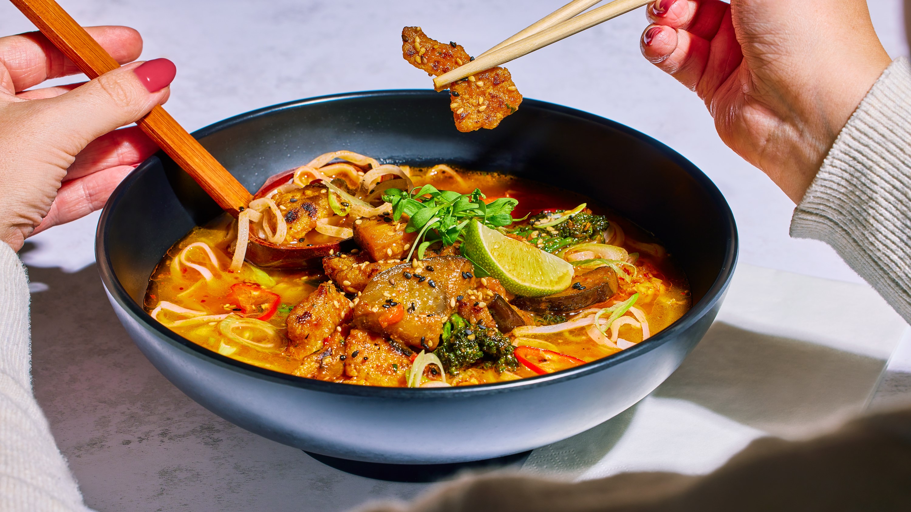firecracker ramen served in a bowl, using chopsticks