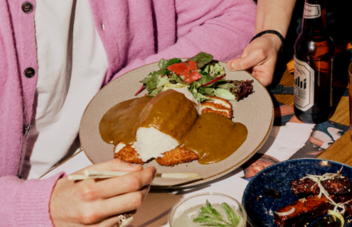 a wagamama team member hands a guest a chicken katsu curry