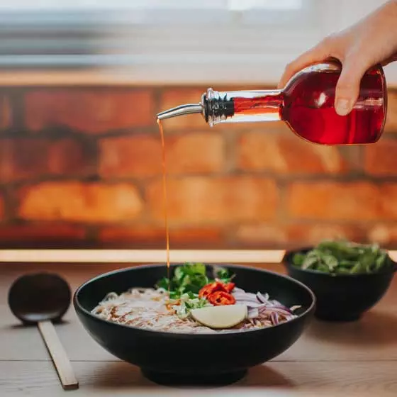 chilli chicken ramen with ladle, side of edamame and chilli oil