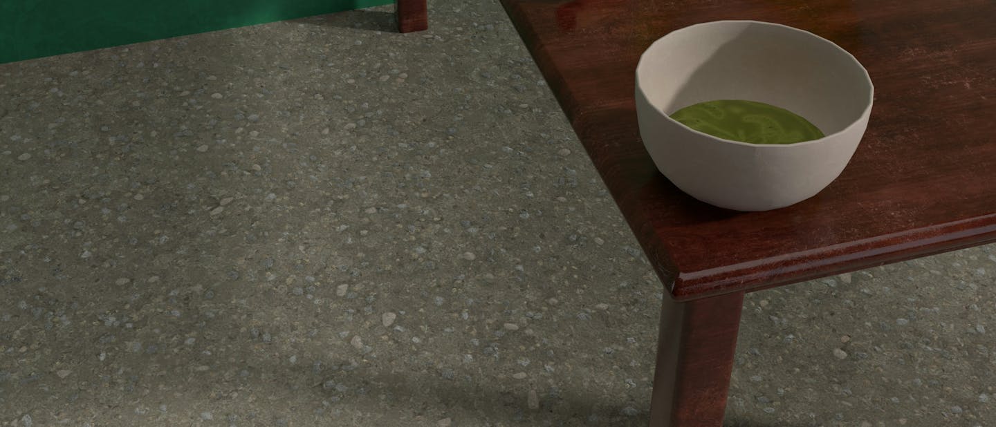 Bowl of matcha on a wooden table with a whisk and green glass vase