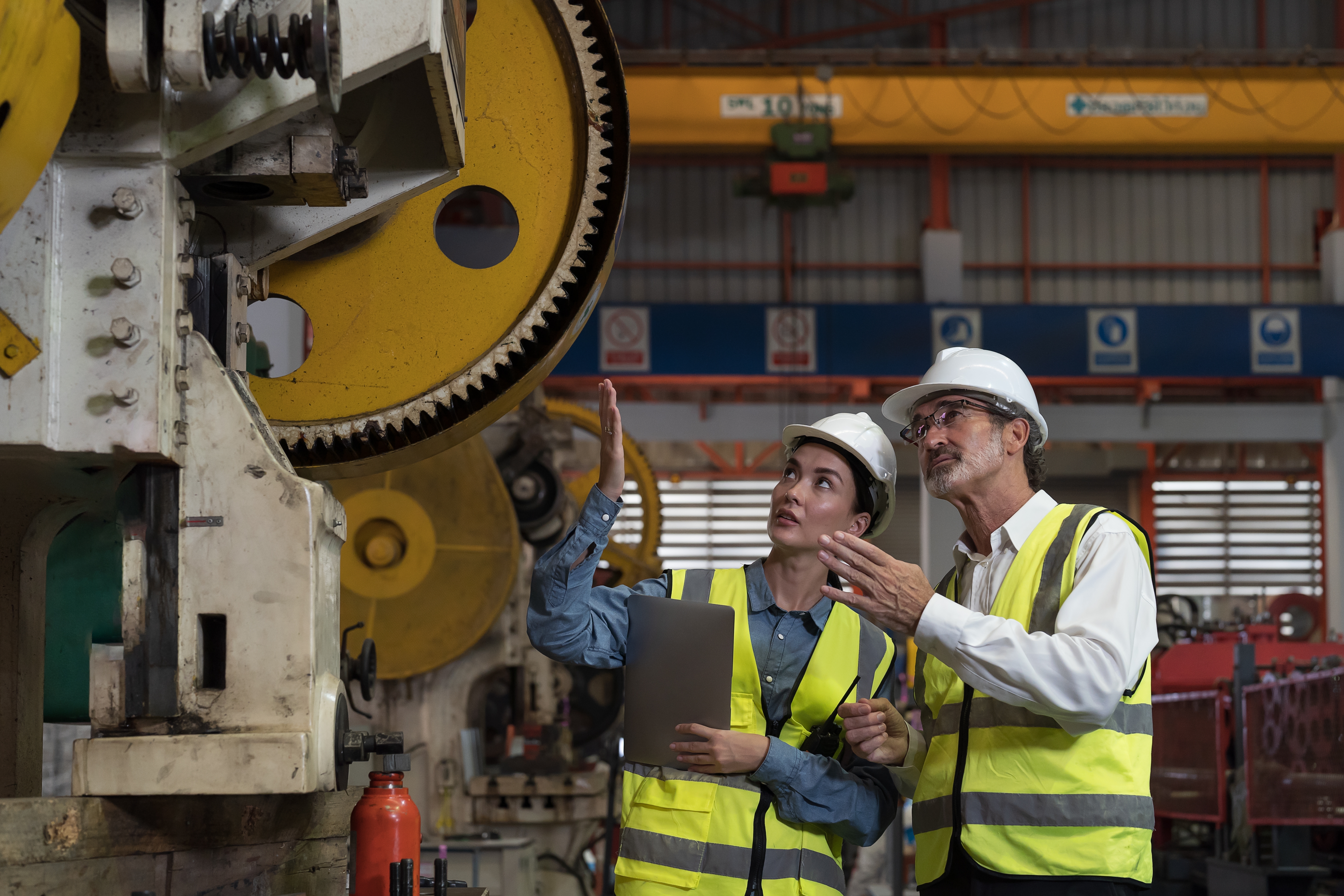 a woman and a men standing next to a machine and looking at the machine