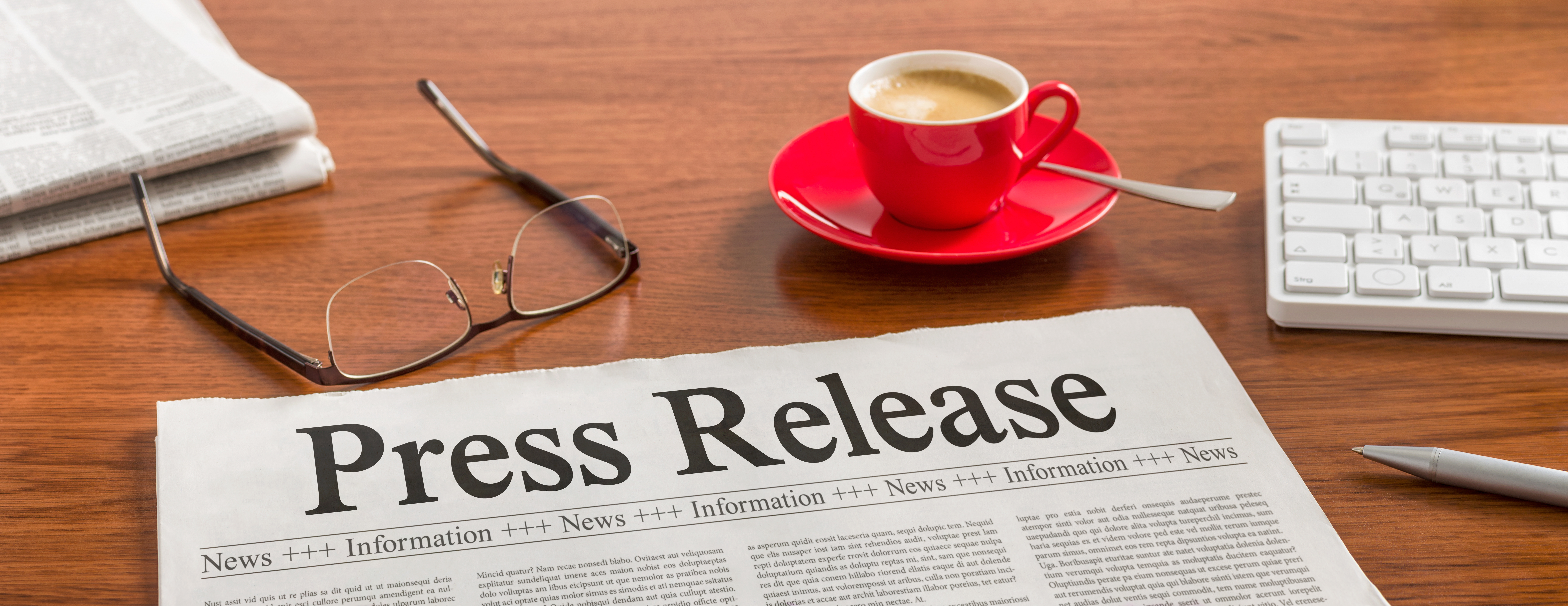 A newspaper placed on a wooden desk with the headline 'Press Release' visible on the front page.