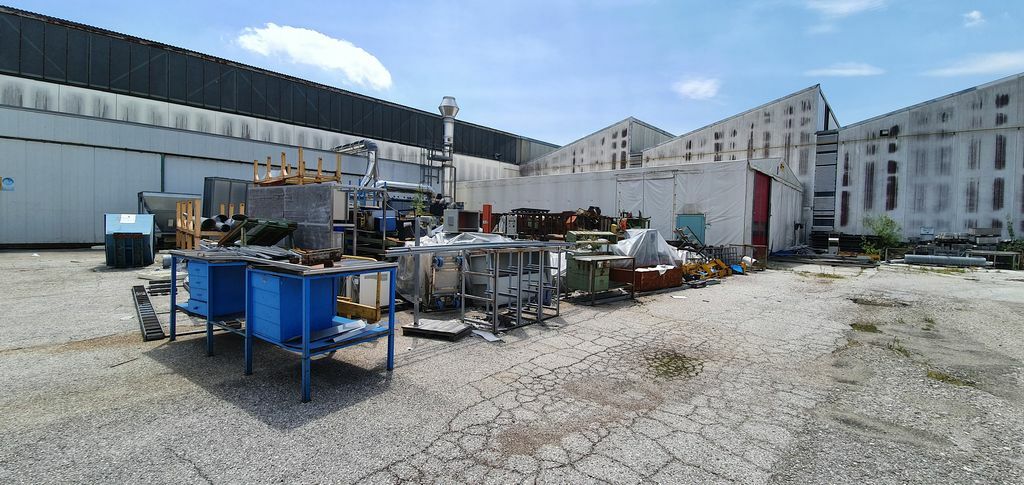Metal scrap piled in the yard of a decommissioned factory, illustrating the recycling potential in industrial plant closures.