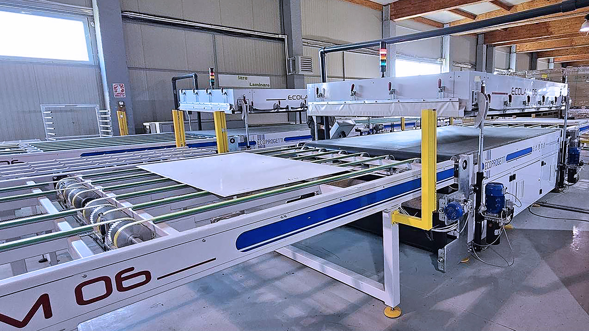 Einfuhrbereich der ECOLAM 06 Laminiermaschine mit einer Glasplatte und noch nicht vernetzter EVA-Folie. Vorbereitung für den Laminierungsprozess in der Solarmodulproduktion.
