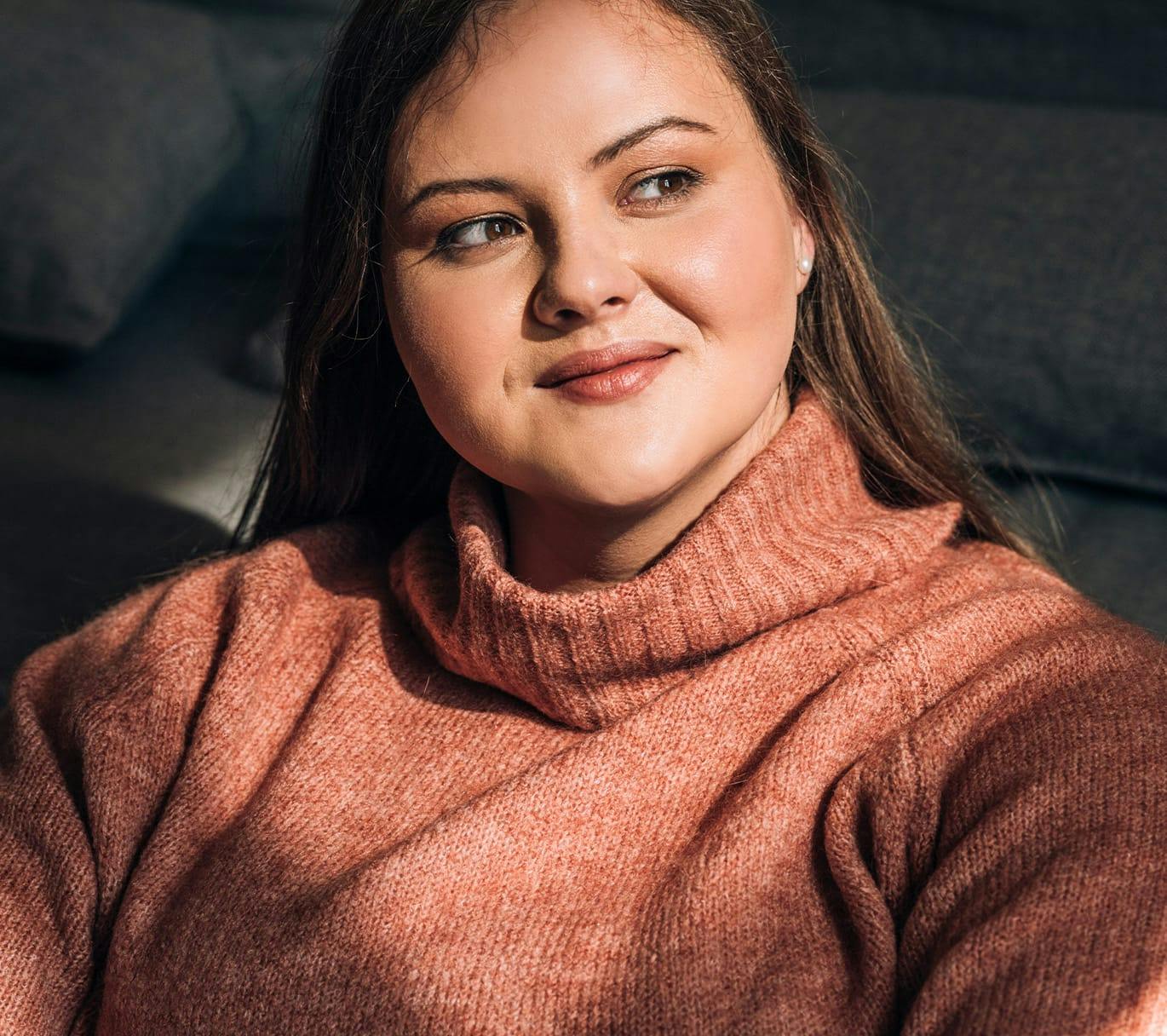 woman looking out window in turtleneck