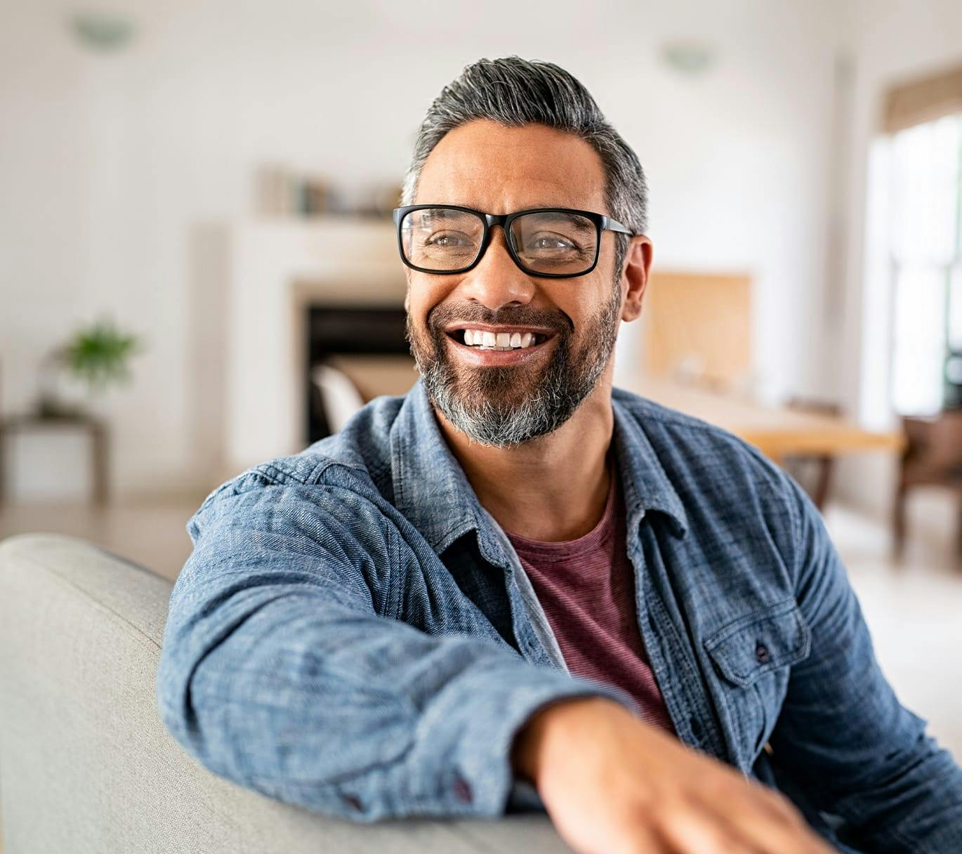 smiling man with glasses sitting on a couch