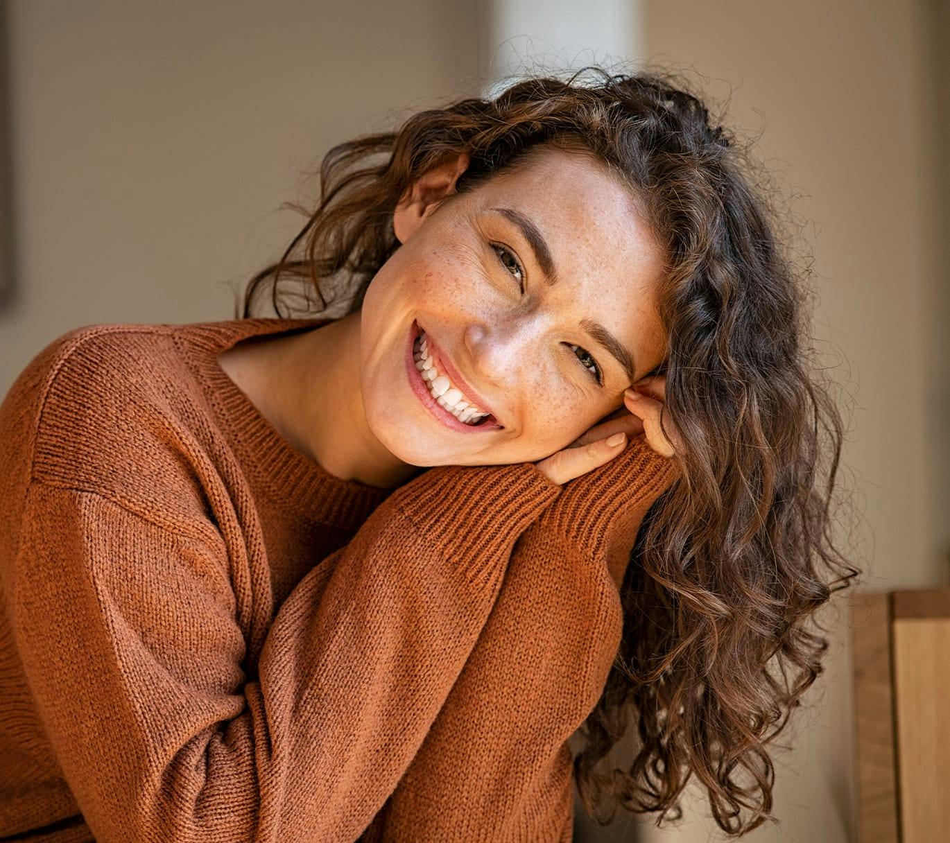 woman smiling in brown sweater