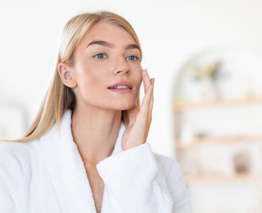 woman in robe touching face