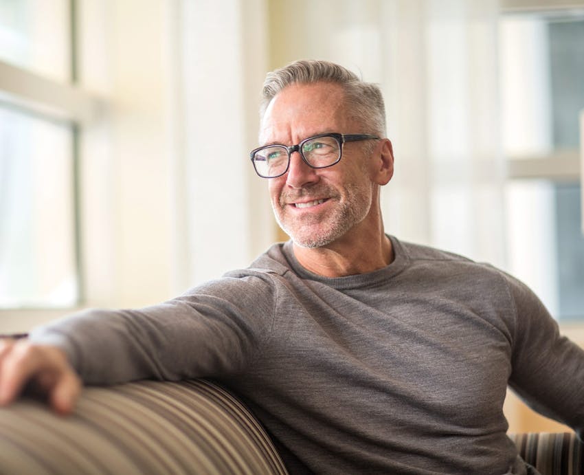 smiling man on a couch wearing glasses