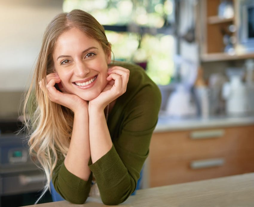 woman smiling with hands under chin