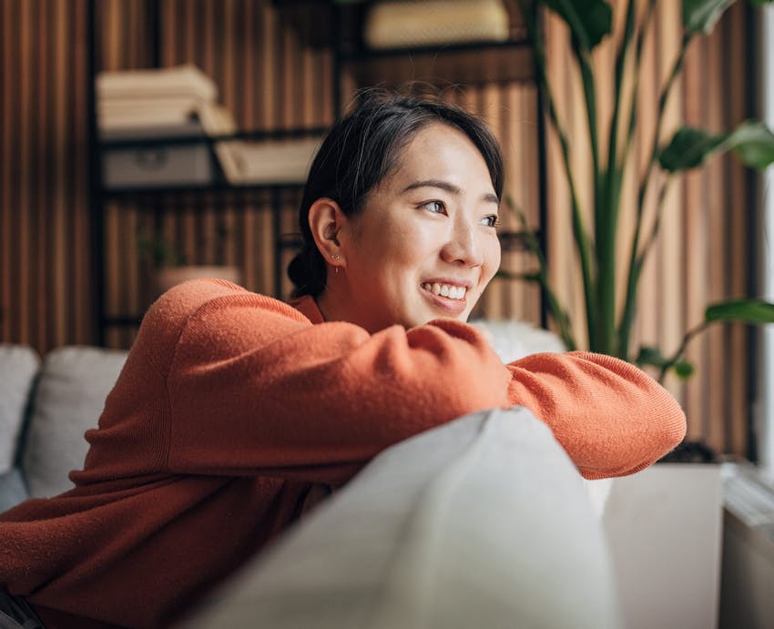 woman leaning on back of couch looking outside