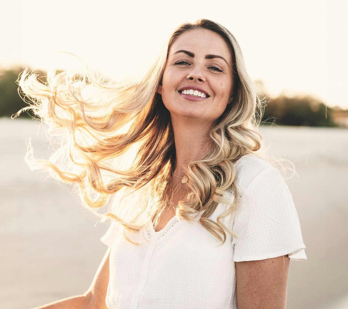 woman with blonde curly hair wearing a white blouse